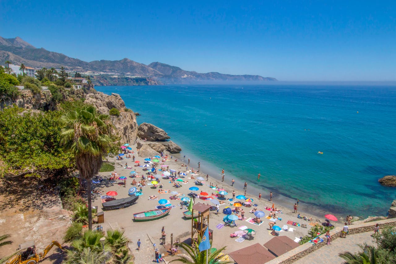 about-us Colorful beach scene at Málaga with umbrellas and people enjoying the summer day.